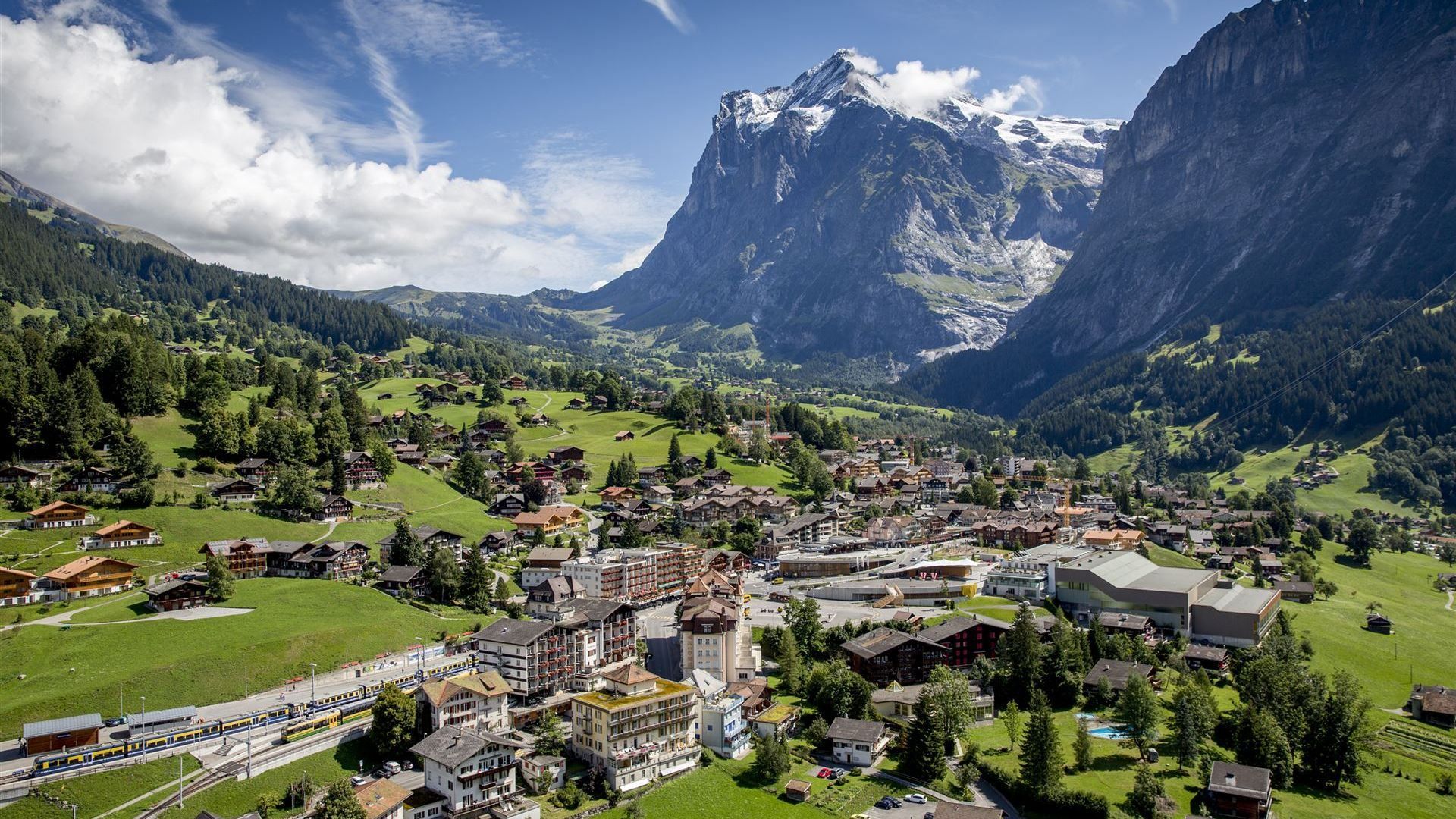 Ort in einem grünen Tal vor der Bergkulisse der Schweizer Alpen