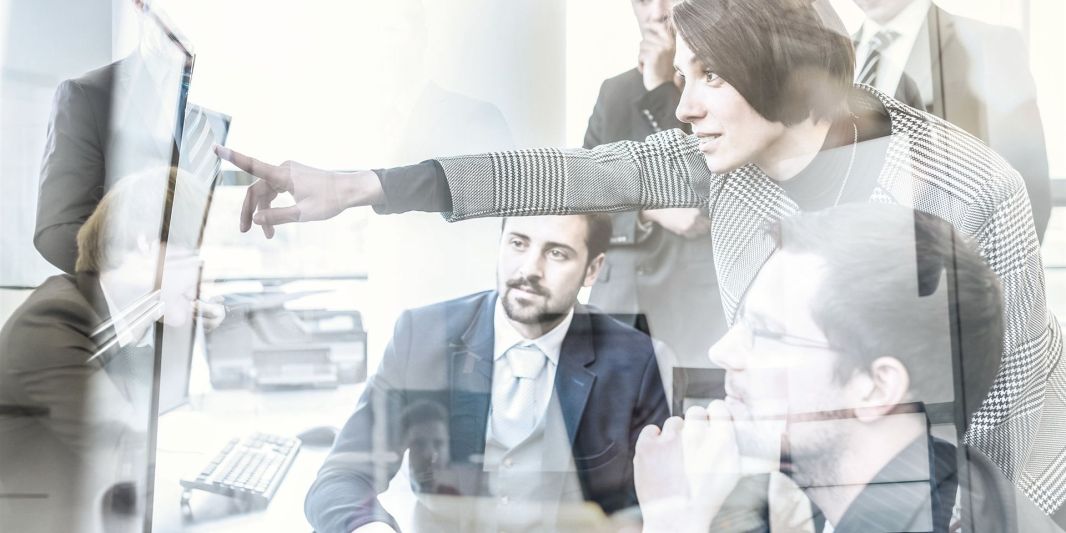 Besprechung an einem Bildschirm – Symbolbild für Zusammenarbeit